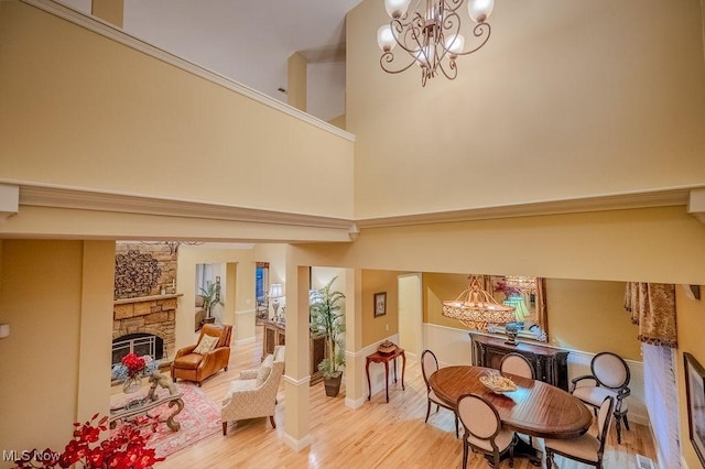 interior space with a high ceiling, wood finished floors, a notable chandelier, and a stone fireplace