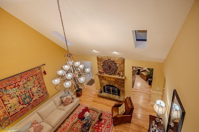 living area featuring an inviting chandelier, a fireplace, vaulted ceiling, and wood finished floors