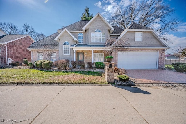 view of front of house featuring roof with shingles, brick siding, decorative driveway, and a front lawn