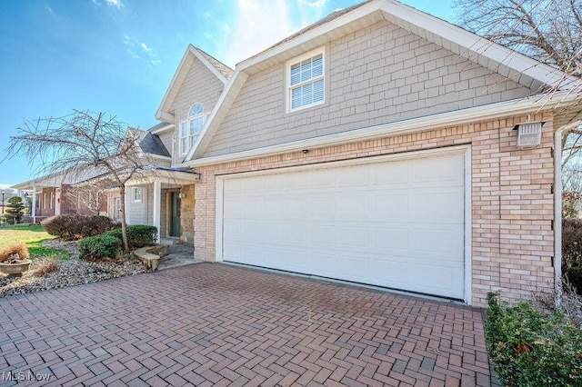 view of front facade featuring a garage, decorative driveway, and brick siding