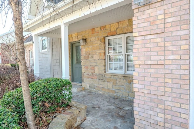 doorway to property with a porch and brick siding