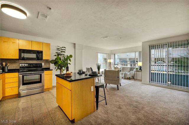 kitchen featuring a breakfast bar, stainless steel electric stove, a textured ceiling, tasteful backsplash, and a kitchen island