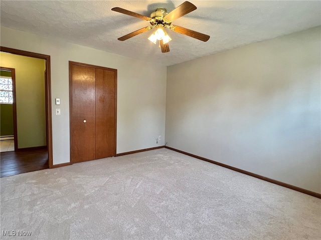 unfurnished bedroom with light carpet, a textured ceiling, ceiling fan, a baseboard radiator, and a closet