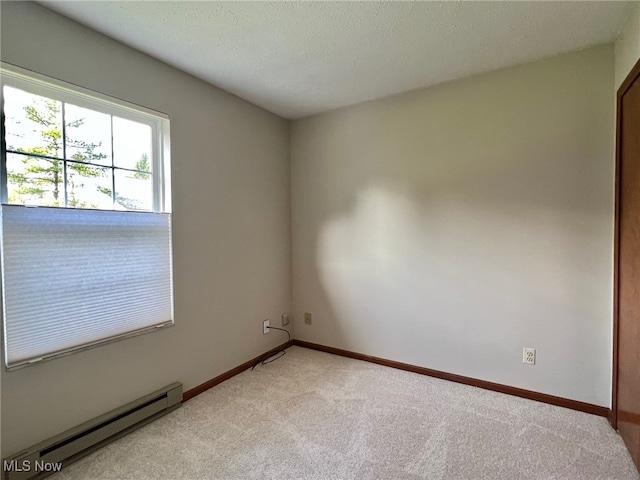 carpeted spare room with a textured ceiling and a baseboard radiator