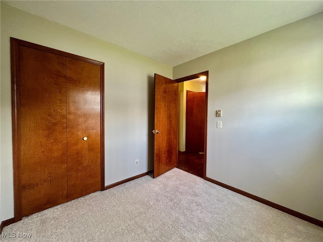 unfurnished bedroom featuring a textured ceiling, carpet floors, and a closet