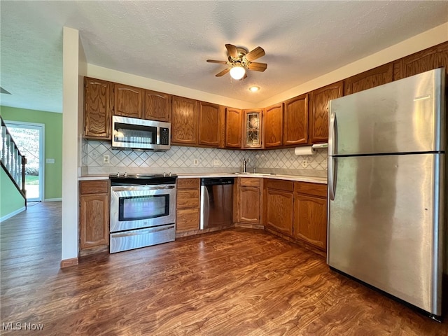 kitchen with a textured ceiling, stainless steel appliances, and dark hardwood / wood-style floors