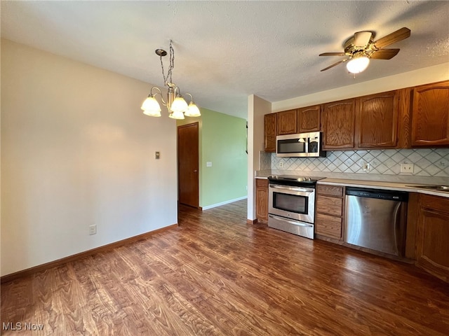 kitchen featuring backsplash, dark hardwood / wood-style flooring, hanging light fixtures, and appliances with stainless steel finishes