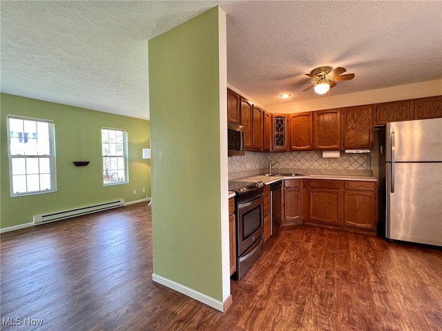 kitchen with baseboard heating, dark hardwood / wood-style flooring, stainless steel appliances, and sink