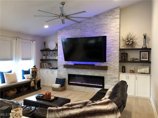 living room featuring ceiling fan, light hardwood / wood-style flooring, a fireplace, and vaulted ceiling