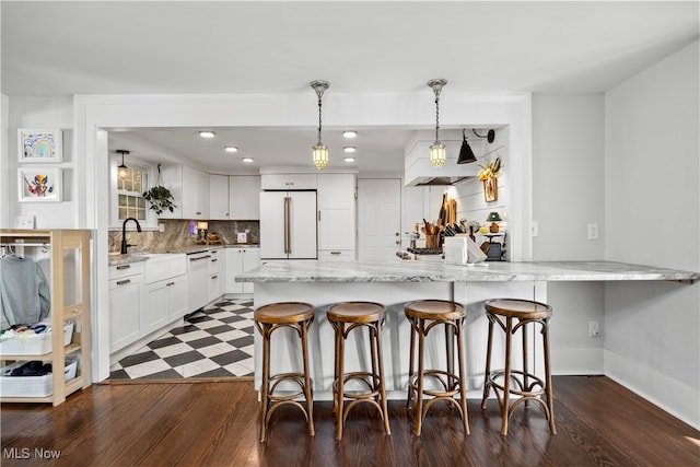 kitchen featuring white appliances, backsplash, light stone counters, white cabinets, and decorative light fixtures