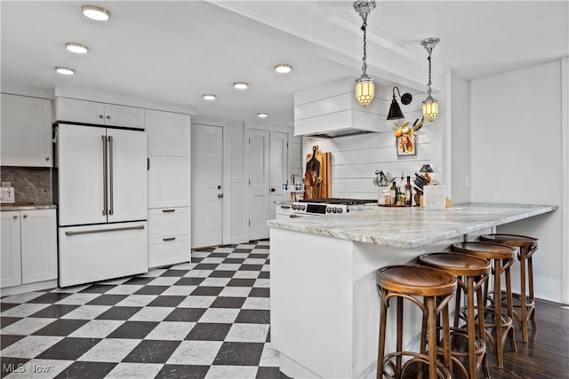 kitchen featuring white cabinetry, premium range hood, high end white fridge, and decorative light fixtures