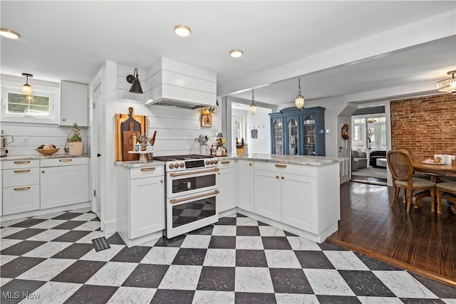 kitchen featuring range with two ovens, premium range hood, white cabinets, and kitchen peninsula