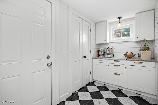 kitchen featuring white cabinetry, light stone countertops, and hanging light fixtures