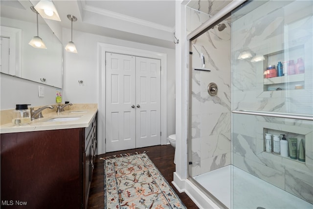 bathroom with crown molding, hardwood / wood-style flooring, a shower with door, vanity, and toilet