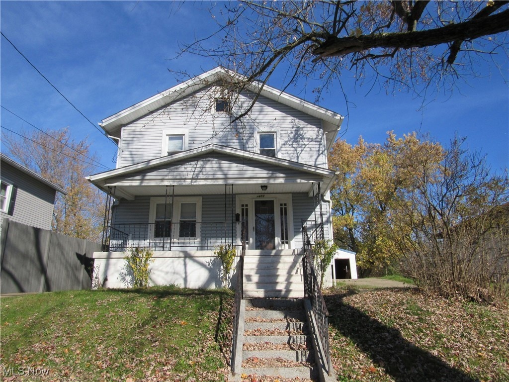 view of front of property featuring an outbuilding, a porch, a garage, and a front lawn