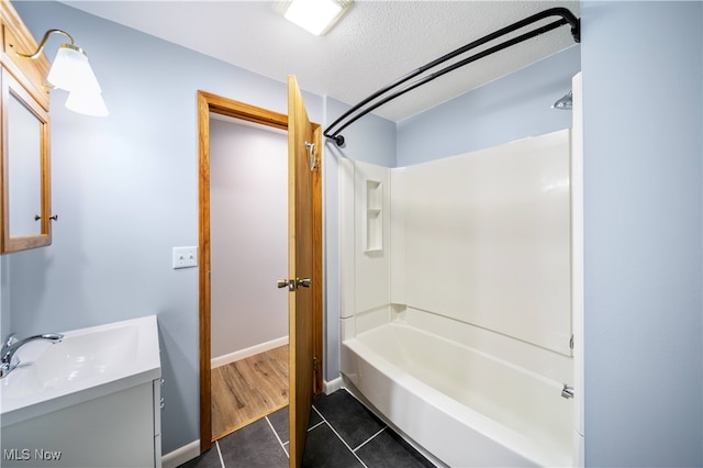 bathroom featuring tile patterned flooring, shower / tub combination, vanity, and a textured ceiling