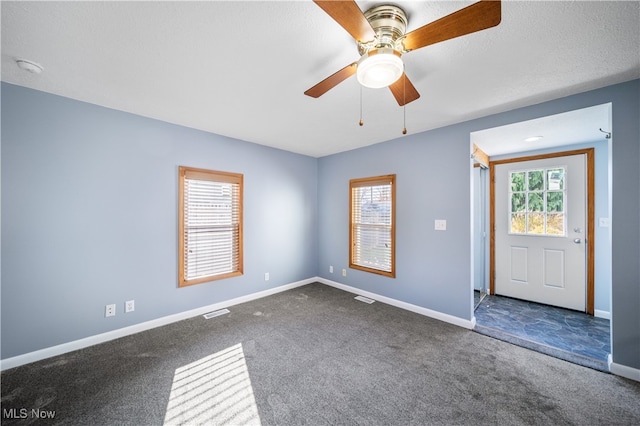 carpeted spare room featuring a textured ceiling, plenty of natural light, and ceiling fan