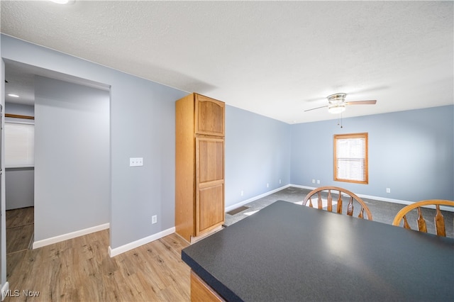 unfurnished dining area featuring ceiling fan, light hardwood / wood-style floors, and a textured ceiling