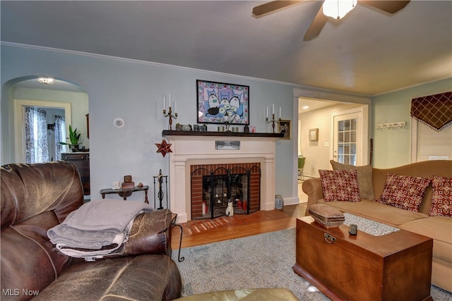 living room with a fireplace, ceiling fan, hardwood / wood-style floors, and ornamental molding