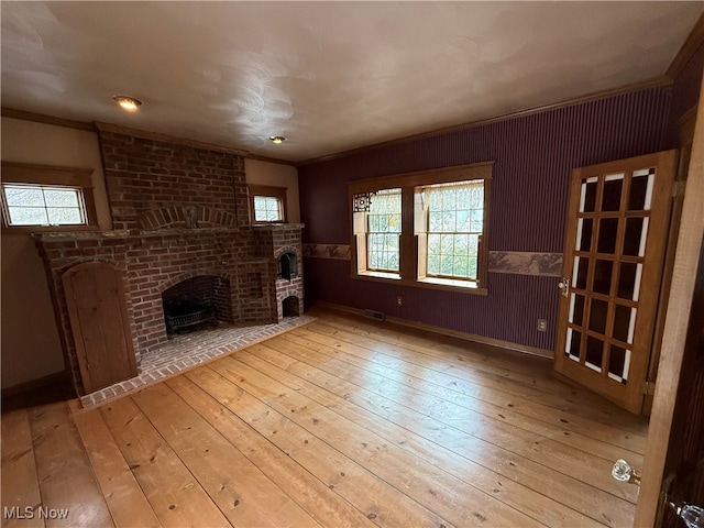 unfurnished living room featuring crown molding, light hardwood / wood-style floors, and a brick fireplace