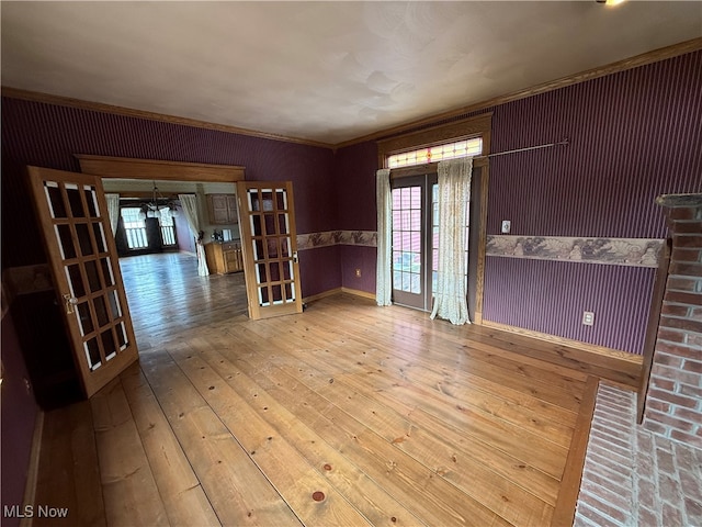 empty room featuring french doors, hardwood / wood-style flooring, and crown molding