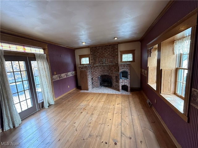 unfurnished living room with light hardwood / wood-style floors, crown molding, and a fireplace