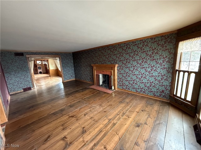 unfurnished living room with wood-type flooring and a brick fireplace