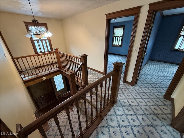 staircase with carpet flooring and a notable chandelier