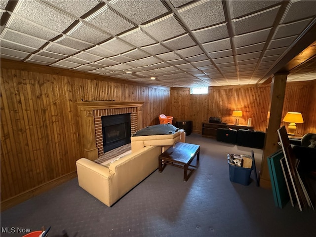 living room featuring a brick fireplace and wooden walls