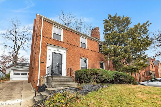 view of front of property with a garage, a front yard, a chimney, and brick siding