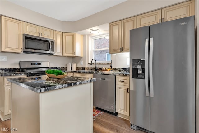 kitchen with sink, a center island, stainless steel appliances, cream cabinets, and light hardwood / wood-style floors