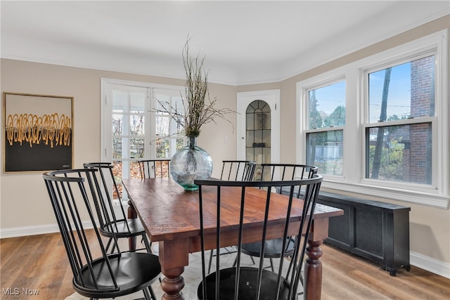 dining area featuring light hardwood / wood-style floors, radiator heating unit, and crown molding