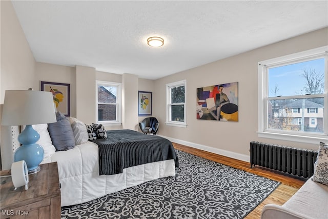 bedroom featuring multiple windows, wood-type flooring, a textured ceiling, and radiator