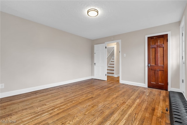 empty room with a textured ceiling and light hardwood / wood-style floors