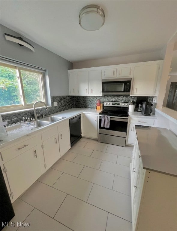 kitchen with sink, light tile patterned flooring, backsplash, white cabinets, and appliances with stainless steel finishes