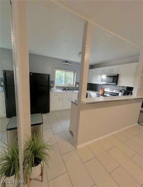 kitchen with decorative backsplash, appliances with stainless steel finishes, light tile patterned floors, and white cabinetry