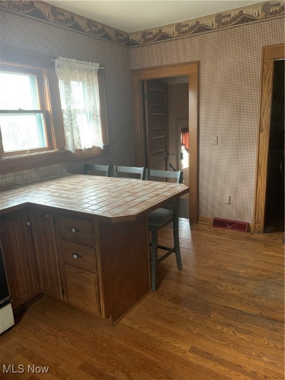 kitchen featuring kitchen peninsula, dark brown cabinetry, and dark hardwood / wood-style flooring