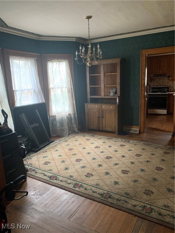 unfurnished dining area featuring a notable chandelier, crown molding, and light hardwood / wood-style flooring