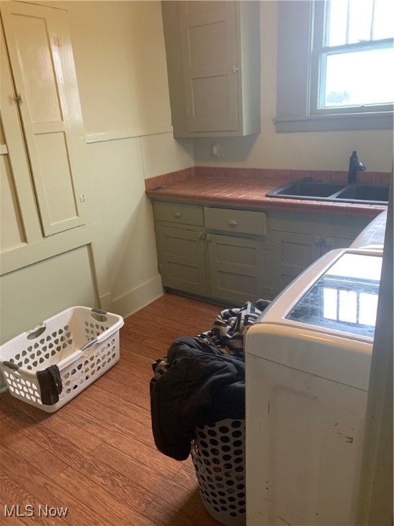 laundry area with cabinets, sink, washer / clothes dryer, and light hardwood / wood-style flooring