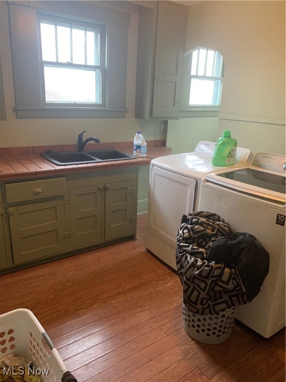 laundry room featuring washer and clothes dryer, plenty of natural light, light wood-type flooring, and sink