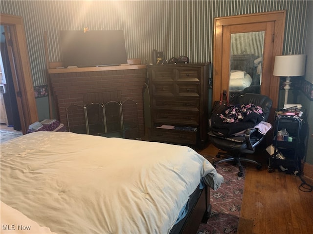 bedroom with a fireplace and wood-type flooring