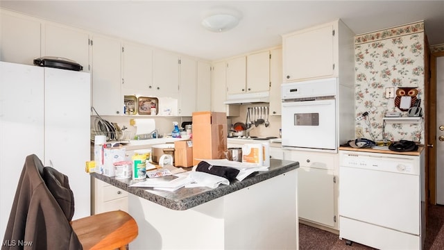 kitchen with a breakfast bar, white cabinets, white appliances, and dark colored carpet