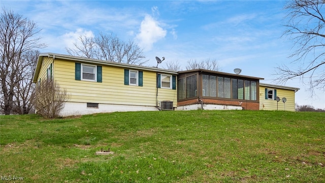 back of house with central air condition unit, a lawn, and a sunroom