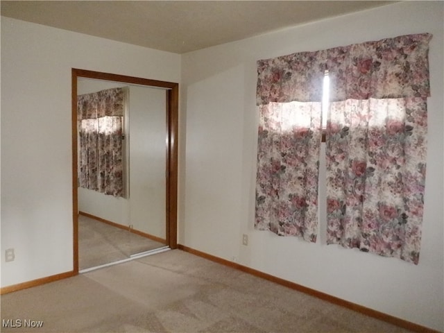 unfurnished bedroom with light colored carpet and a closet