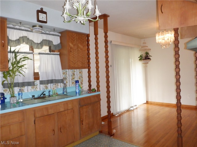 kitchen featuring a chandelier, light wood-type flooring, decorative light fixtures, and sink