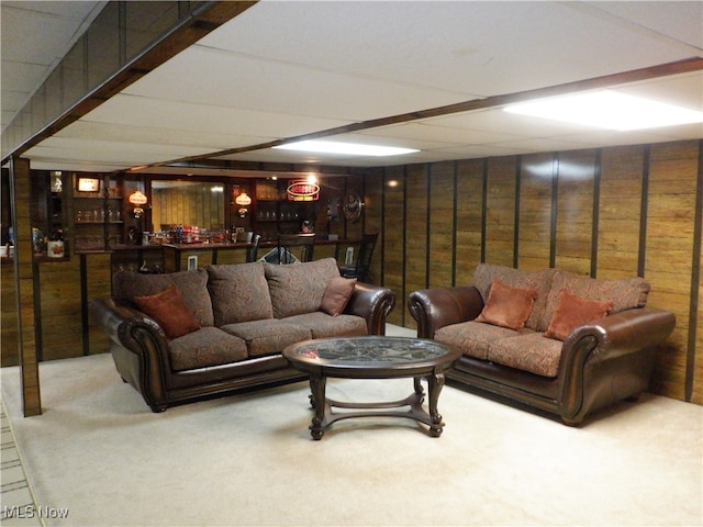 living room featuring carpet flooring, bar area, and wood walls