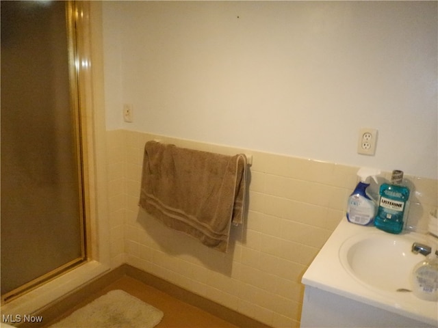 bathroom with an enclosed shower, sink, and tile walls