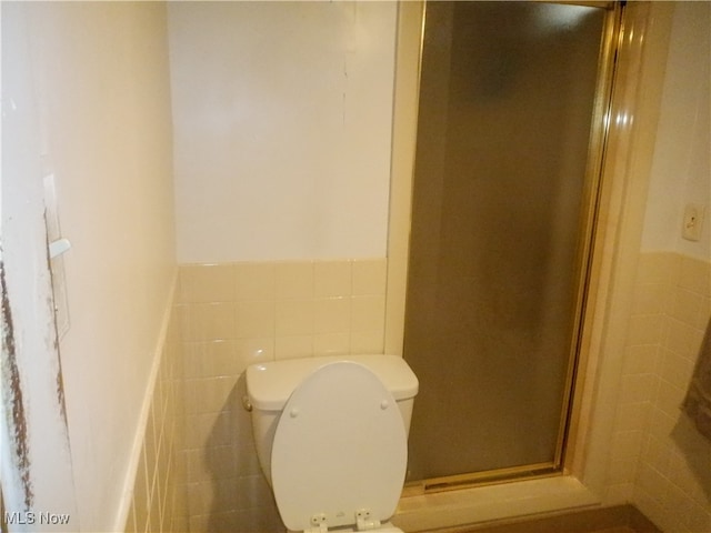 bathroom with an enclosed shower, tile walls, and toilet