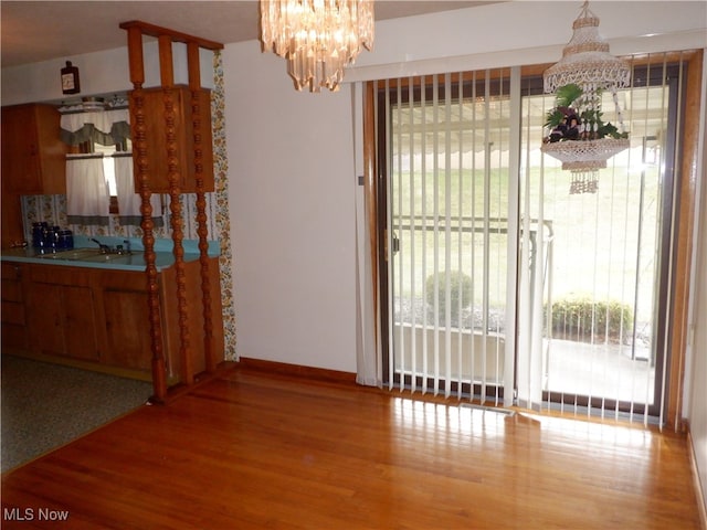 dining space with sink, hardwood / wood-style floors, and a notable chandelier