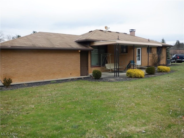 rear view of property featuring a lawn and a patio area